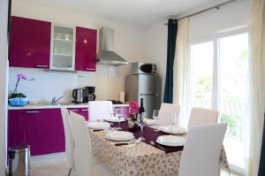 a kitchen with a table with white chairs and purple cabinets at Apartment A. Žižić in Slatine