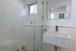 La salle de bains blanche est pourvue d'un lavabo et d'un miroir. dans l'établissement New Cumberland 501 by CTHA, au Cap