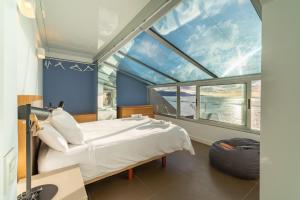 a bedroom with a bed and a large window at Living Las Canteras Homes - BEACHFRONT ROOFTOP in Las Palmas de Gran Canaria