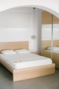 a bedroom with a large white bed with a wooden headboard at Ktima Tzaneti in Lachania