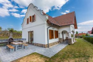 ein kleines weißes Haus mit einer Terrasse und einem Tisch in der Unterkunft VIVAZA Villa Szigliget in Szigliget