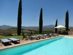 a swimming pool with benches and tables and an umbrella at Agriturismo La Casaccina in Trevinano