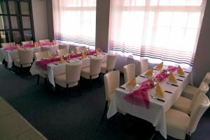 un comedor con mesas blancas y sillas con arcos rosados en Hotel ELMA, en Srbsko