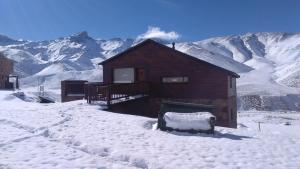 a cabin in the snow with mountains in the background at Villa Montaña in Las Lenas