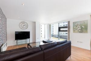 a living room with a couch and a clock on the wall at Stylish Garden View Apartment in Edinburgh