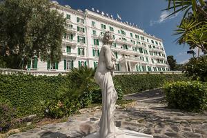 Una statua di una donna davanti a un edificio di Grand Hotel & des Anglais Spa a Sanremo