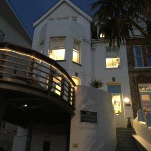 a white house with a porch and a building at The White House Hotel in Newquay