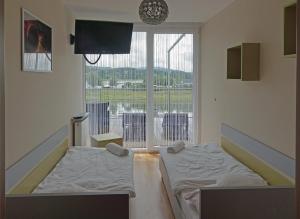 Habitación con 2 camas y ventana grande. en Apartment Słoneczny Gródek 19 Spa & Wellness, en Gródek Nad Dunajcem