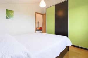 a bedroom with a white bed and a green wall at Sunset View Apartment in Zadar
