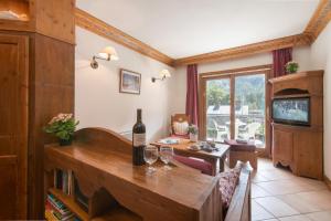 een woonkamer met een tafel met een fles wijn bij Résidance Le Cristal - Grands Montets 11 - Happy Rentals in Chamonix-Mont-Blanc