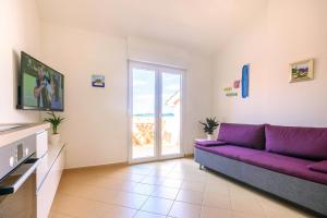 a living room with a purple couch and a window at Sunset View Apartment in Zadar