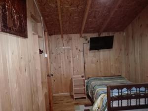 a bedroom with a bed and a flat screen tv at Hospedaje Los Calafates in Ancud