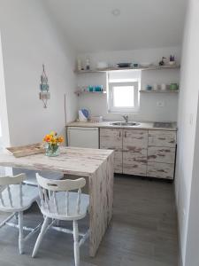 a kitchen with a wooden table and two white chairs at Apartments and Rooms Lijesevic in Budva