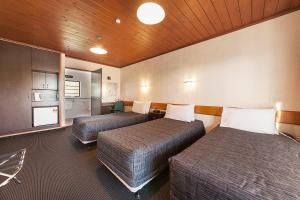 two beds in a small room with a kitchen at Lakeland Resort Taupo in Taupo