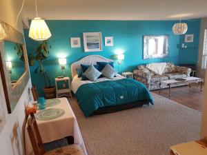 um quarto azul com uma cama e um sofá em Davis Bay Bed & Breakfast em Sechelt