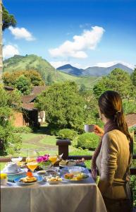 Eine Frau, die an einem Tisch sitzt und Essen drauf hat. in der Unterkunft Pousada Terra da Luz in Visconde De Maua