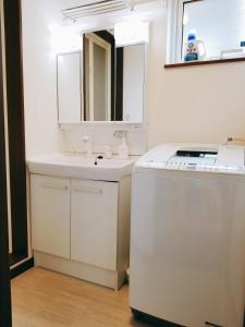 a white bathroom with a sink and a dishwasher at Kashiwa House Furano in Furano