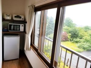 a kitchen with a large window and a refrigerator at Kashiwa House Furano in Furano