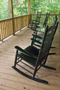 a row of rocking chairs sitting on a deck at The Dogwood Breeze in Aquone