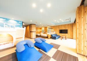 a living room with wooden walls and a large room with blue chairs at Meijikan in Izu