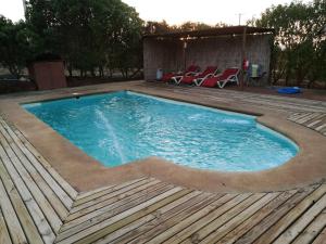 una piscina con una terraza de madera y sillas. en lodge con piscina privada, parcela de campo., en Algarrobo
