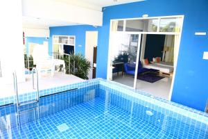 a swimming pool in a house with a blue wall at Kata Sea Host in Kata Beach