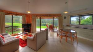 a kitchen and living room with a table and chairs at Whispering Pines Cottages in Burnt Pine