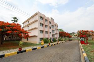 a building on the side of a road with flowering trees at Ramoji Greens Inn in Pedda Ambarpet