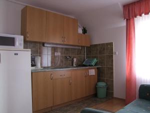 - une cuisine avec des placards en bois et un four micro-ondes dans l'établissement Rajna Apartmanház, à Bogács