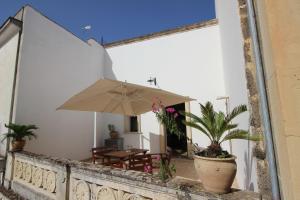 eine Terrasse mit einem Tisch und einem Sonnenschirm in der Unterkunft Home Holiday Salento Casa Agrosì Don Camillo in Presicce