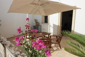 eine Terrasse mit einem Tisch, einem Sonnenschirm und Blumen in der Unterkunft Home Holiday Salento Casa Agrosì Don Camillo in Presicce