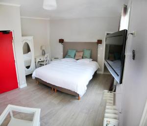 a bedroom with a white bed and a flat screen tv at Hôtel de France in Lillebonne