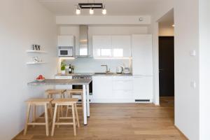 a kitchen with white cabinets and a table and stools at Cosy city apartment in Pärnu