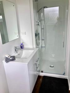 a white bathroom with a sink and a shower at Otaki Beachfront Getaway in Otaki Beach