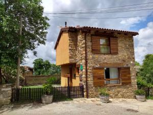 uma pequena casa de pedra com uma cerca em Campillo em Berzosa del Lozoya