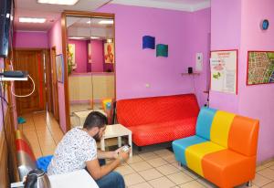 a man sitting in a room with colorful chairs at City Center Hostel in Kyiv