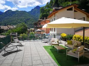 a patio with chairs and an umbrella and mountains at Casa Luca e Cristina in Mezzolago