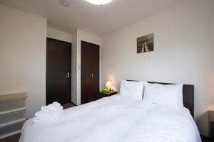 a bedroom with a large white bed with white pillows at Asuka in Niseko