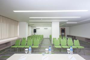 a room with green chairs and bottles of water on tables at MaxOneHotels at Dharmahusada Surabaya in Surabaya