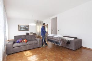 a man standing in a living room with a couch at Hotel del Mar in Sottomarina