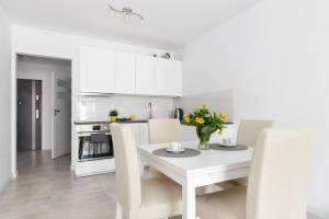 - une cuisine blanche avec une table et des chaises blanches dans l'établissement Good Time Apartments Strzelecka B, à Poznań