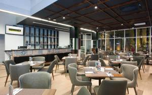 a restaurant with tables and chairs and a bar at MaxOneHotels at Dharmahusada Surabaya in Surabaya