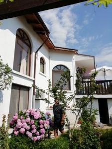a man standing in front of a house with pink flowers at South Beach Villa in Sinemorets