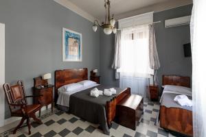 a bedroom with two beds and a chair at Talia B&B Guest House in Reggio Calabria
