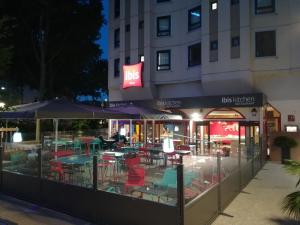 um restaurante com mesas e cadeiras em frente a um edifício em ibis Lyon Part Dieu Les Halles em Lyon