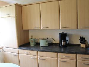 a kitchen with wooden cabinets and a counter top at Cozy Apartment with Garden Barbecue Bicycle Storage in Neubukow