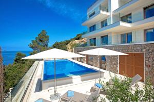a villa with a swimming pool and two umbrellas at Villa Malo More in Dubrovnik