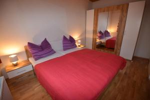 a bedroom with a large red bed with purple pillows at PirkerHof in Wenischgraben