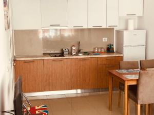 cocina con armarios blancos, mesa y nevera en Viktoria's Apartments, en Shëngjin