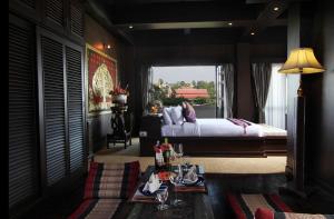 a bedroom with a bed and a table with drinks on it at Singha Montra Lanna Boutique Style Hotel in Chiang Mai